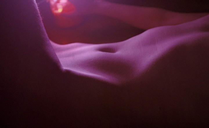 A person's torso is illuminated by a warm, purple light.