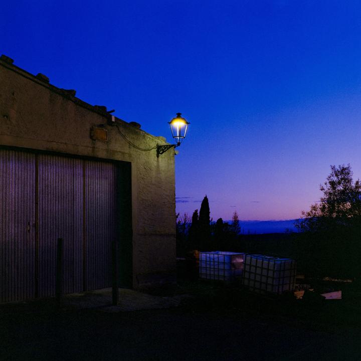 A bright streetlamp illuminates the side of a building with large wooden doors under a deep blue twilight sky.
