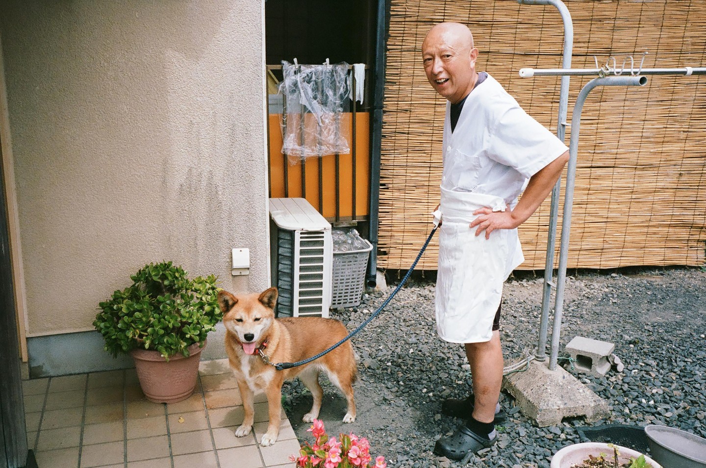 A man in a white chef's coat stands next to a dog on a leash.