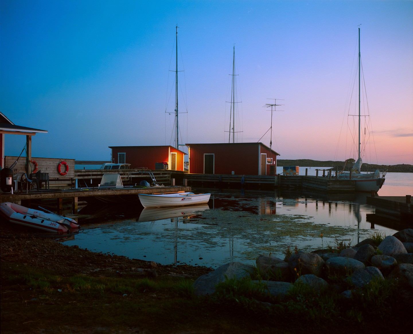 A small harbor with boats and red buildings is visible at dusk.