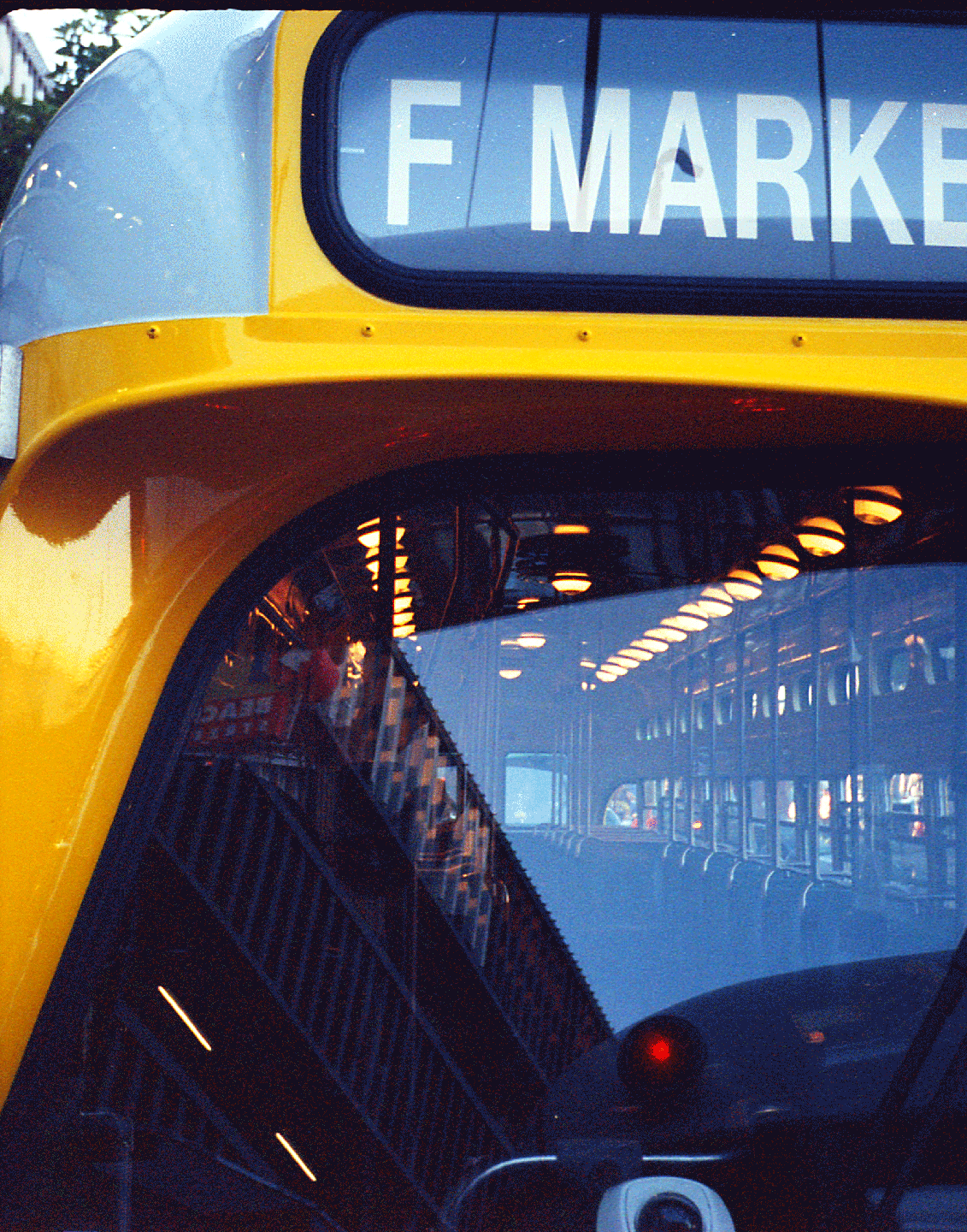 A yellow and gray bus with "F MARKE" on its destination sign reflects the interior of another bus.