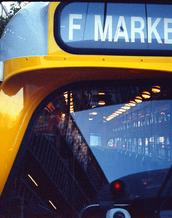 A yellow and gray bus with "F MARKE" on its destination sign reflects the interior of another bus.