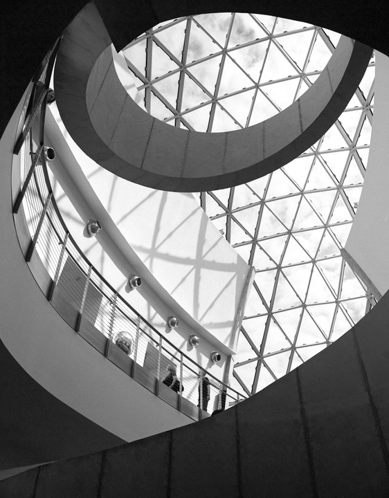 Three women stand on a curved balcony overlooking a geodesic dome ceiling.