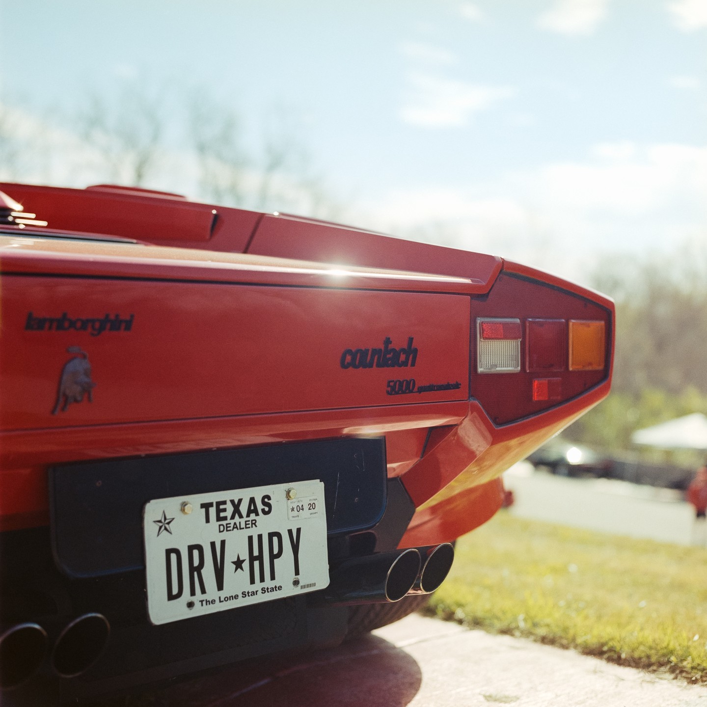 The rear of a red Lamborghini Countach is parked on a paved surface with a Texas license plate.