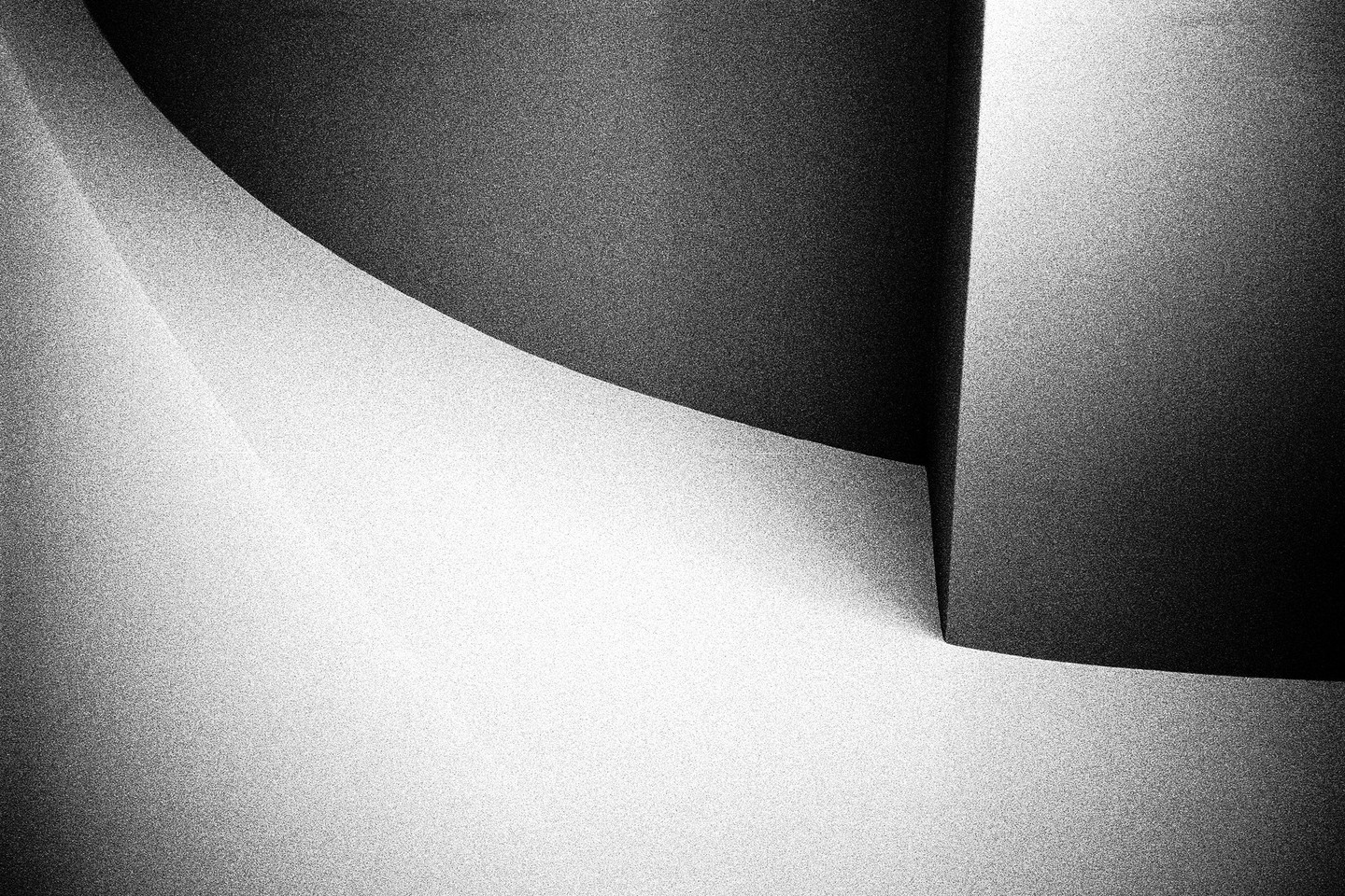 A black and white abstract image shows a curved line separating a dark area from a light area, with a sharp corner in the bottom right.
