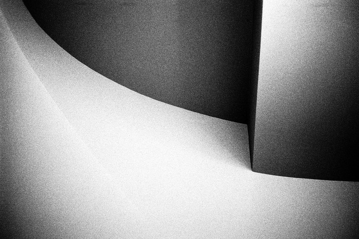 A black and white abstract image shows a curved line separating a dark area from a light area, with a sharp corner in the bottom right.