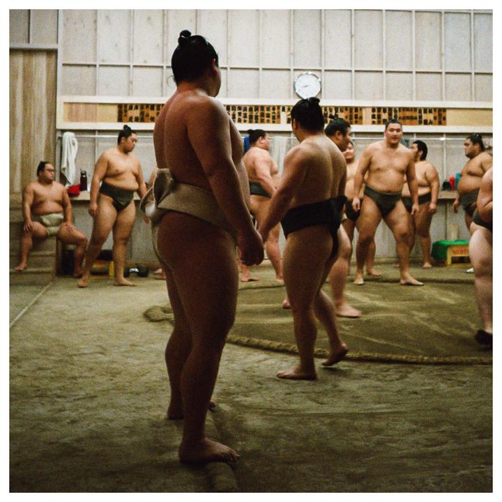 A group of sumo wrestlers are gathered in a practice room.