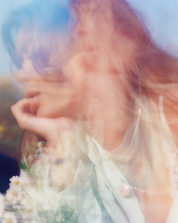 A woman with long hair and a necklace is visible in a blurry, double exposure portrait.
