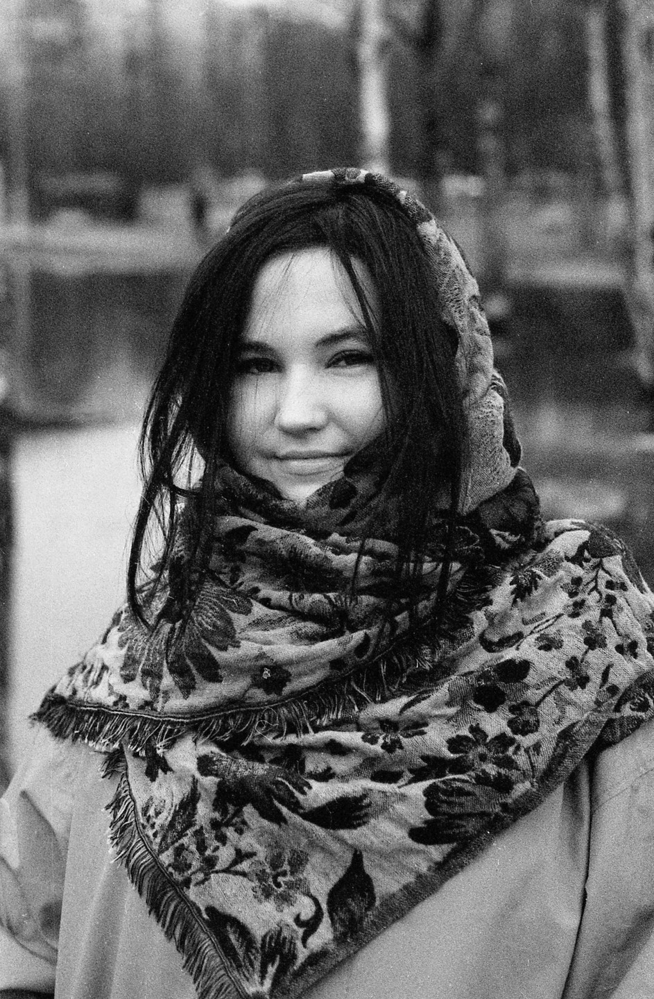 A woman with dark hair and a patterned scarf smiles at the viewer.