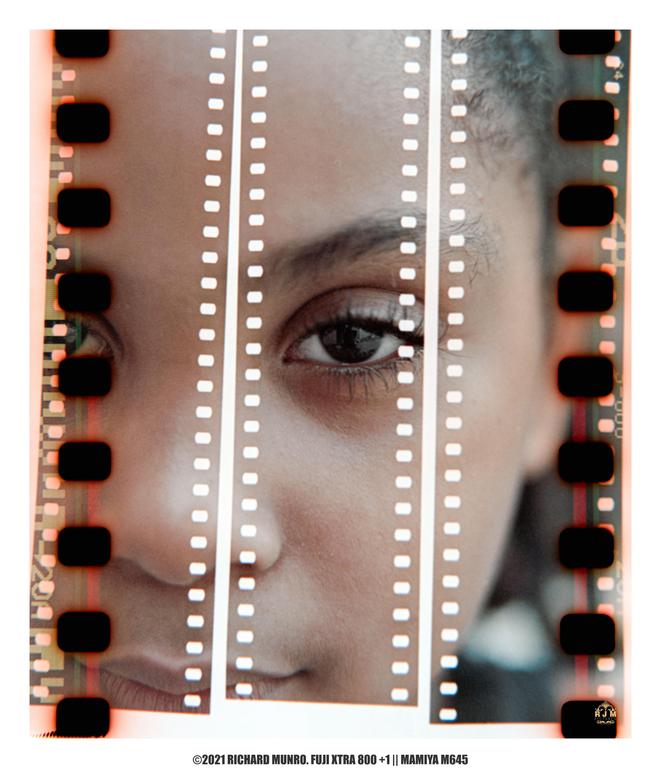 A woman's face is visible through the sprockets of a film strip.