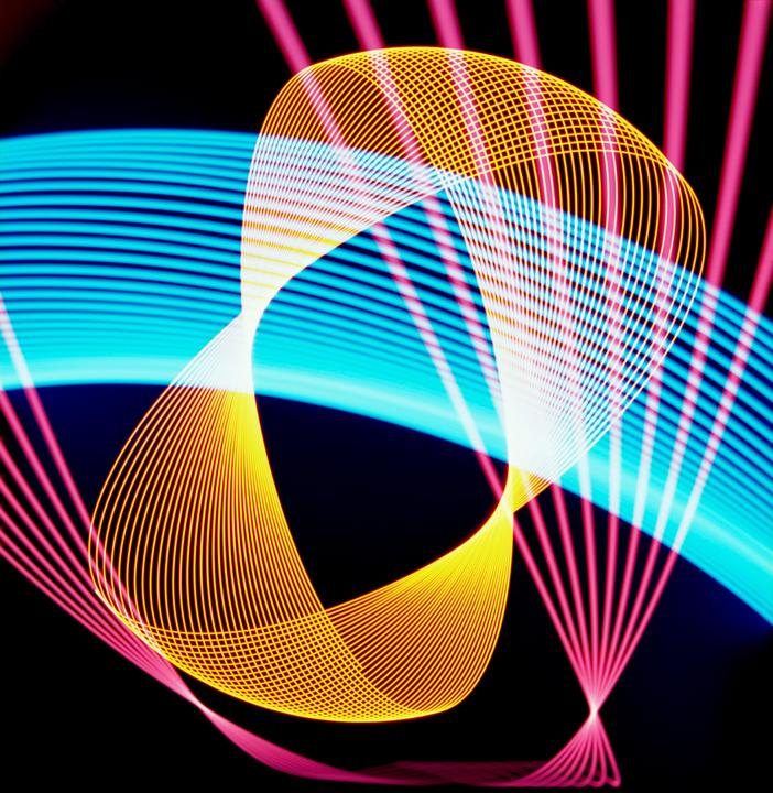 Multiple overlapping light patterns in blue, pink, and yellow are visible against a dark background.