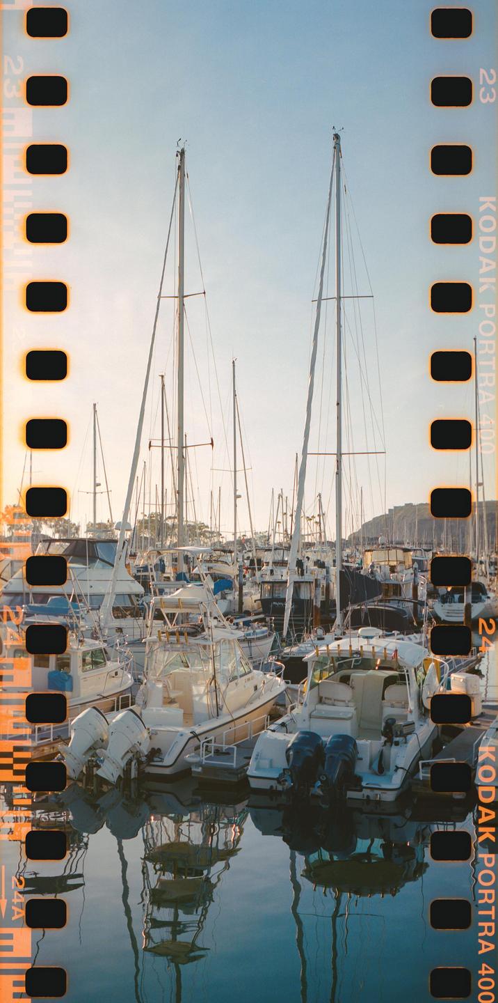 A marina is filled with many boats and sailboats under a bright sky.