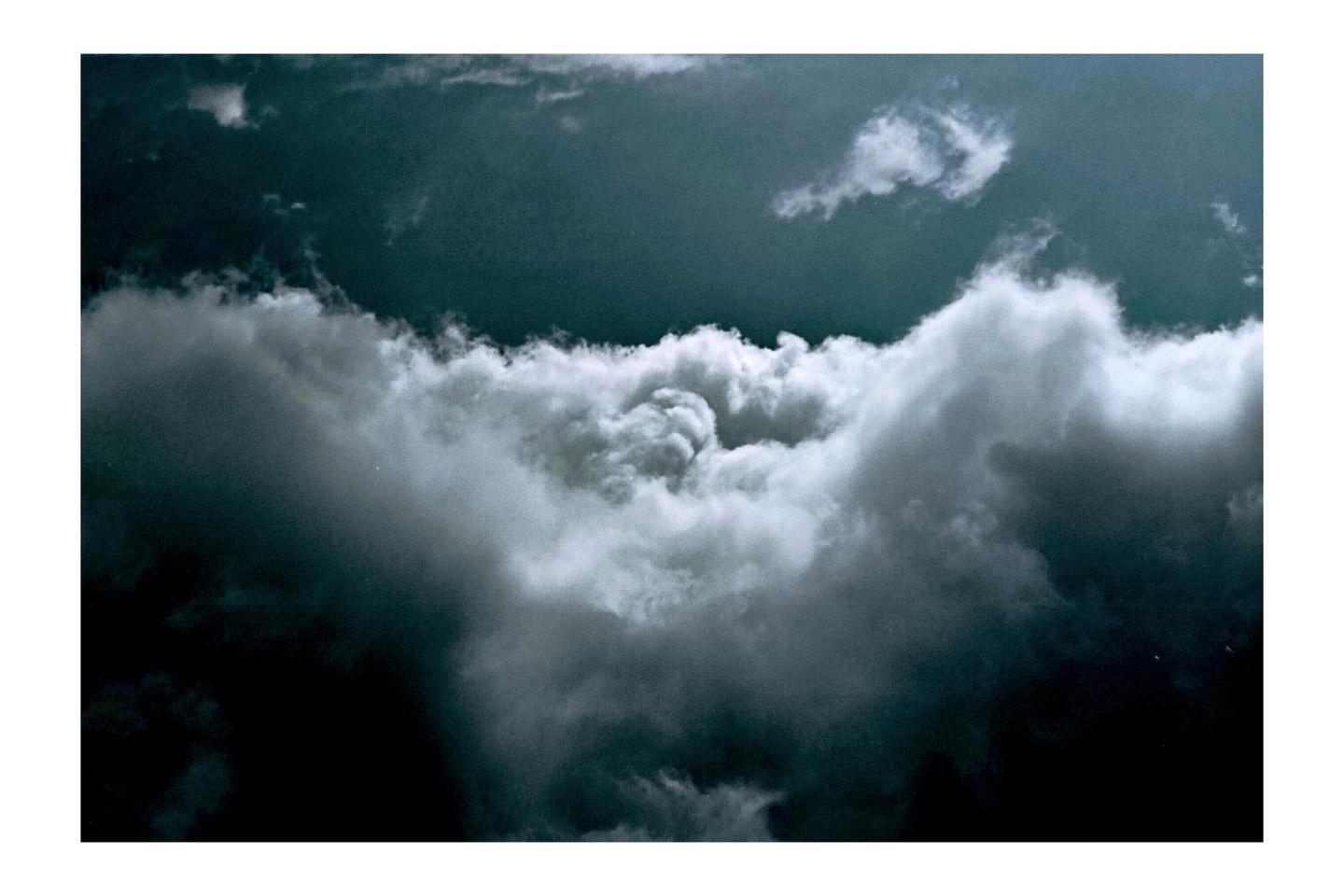 A dark sky is visible above and below a thick band of white and gray clouds.