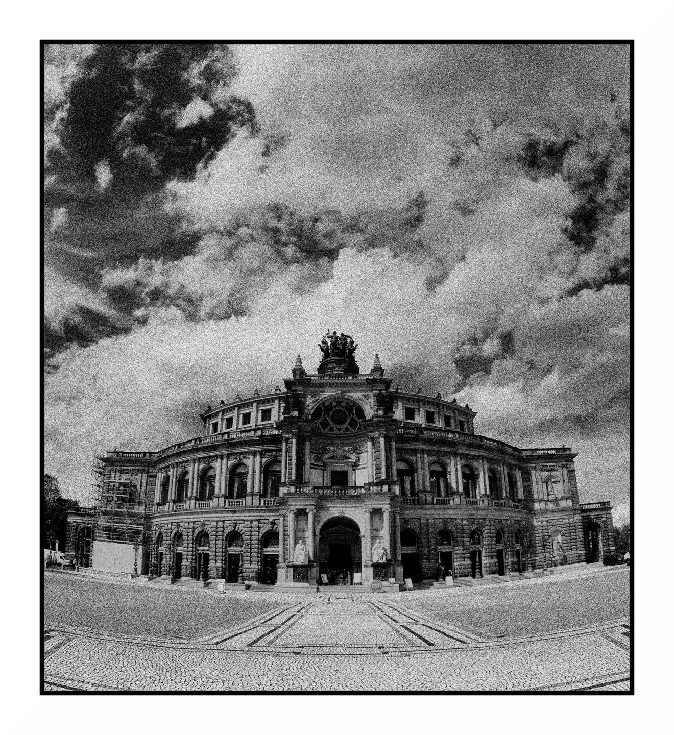 A grand, ornate building with a domed roof and statues stands under a cloudy sky.