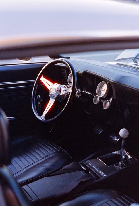 The interior of a vintage car shows a steering wheel, dashboard, and gear shift.