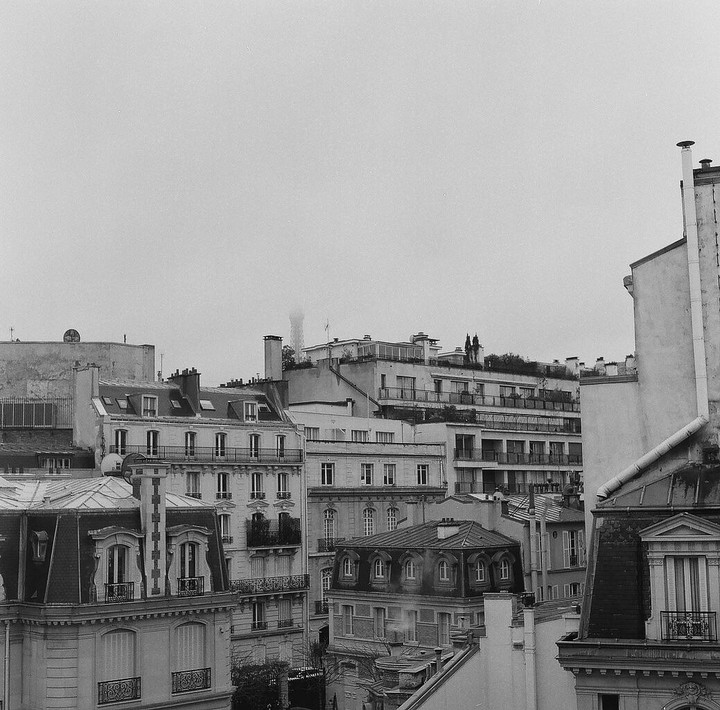A hazy cityscape of parisian buildings with the Eiffel Tower visible in the distance.