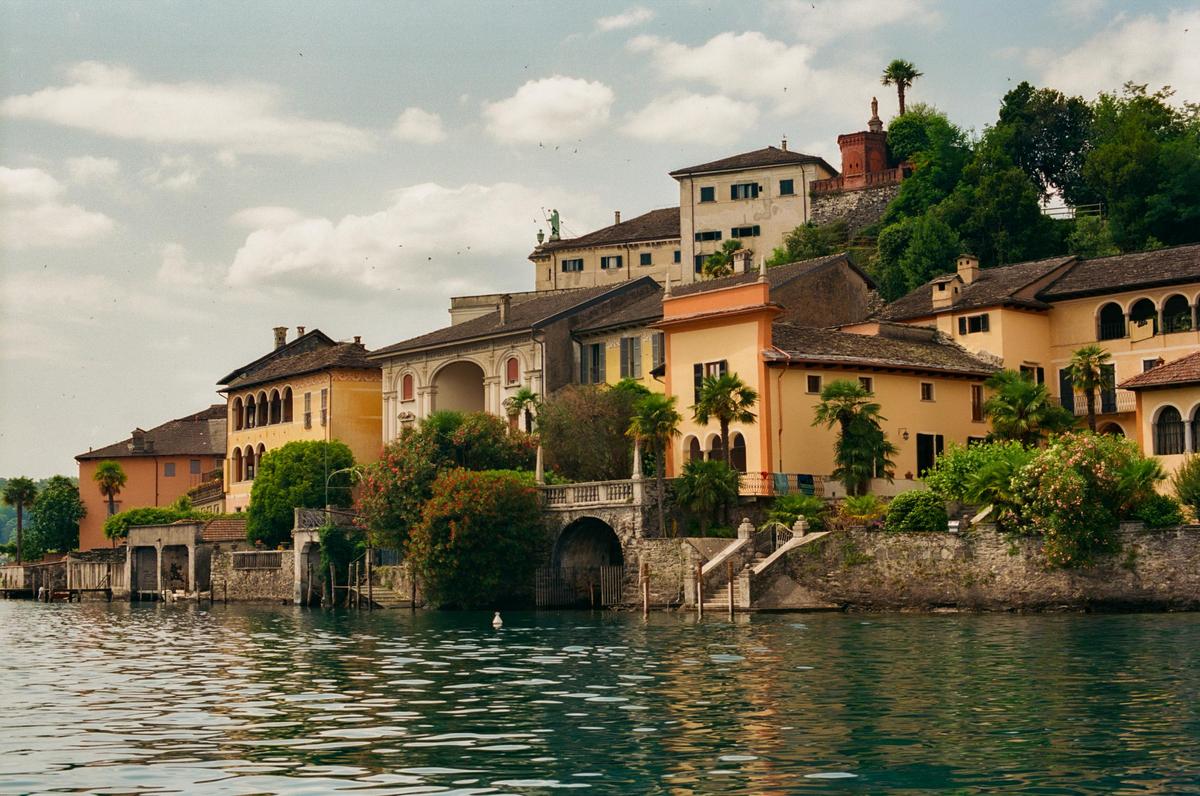 A town with buildings of various colors and styles is built into a hillside overlooking a lake.