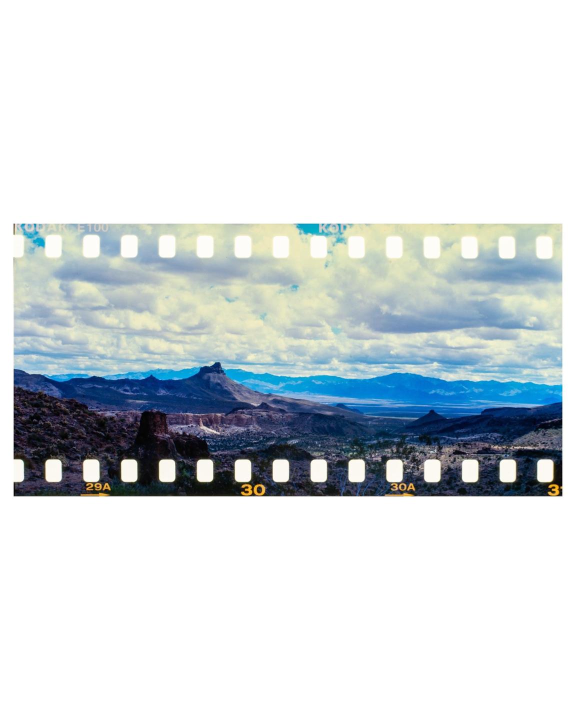 A vast desert landscape with mountains under a cloudy sky is visible.