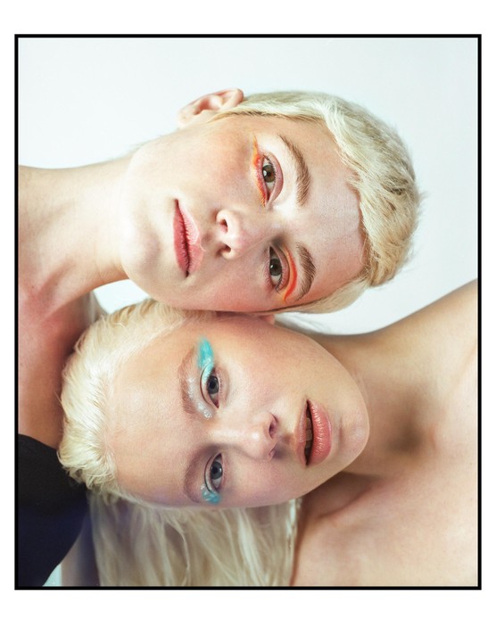 Two women with colorful eye makeup are shown with their heads layered on top of each other.