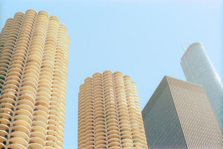 Three skyscrapers with different architectural styles rise against a clear sky.