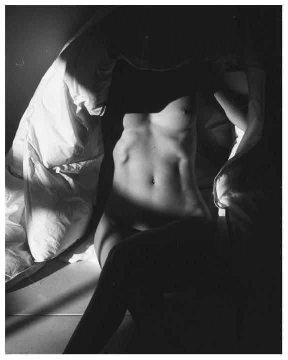A woman's torso is visible in a high contrast black and white self-portrait.