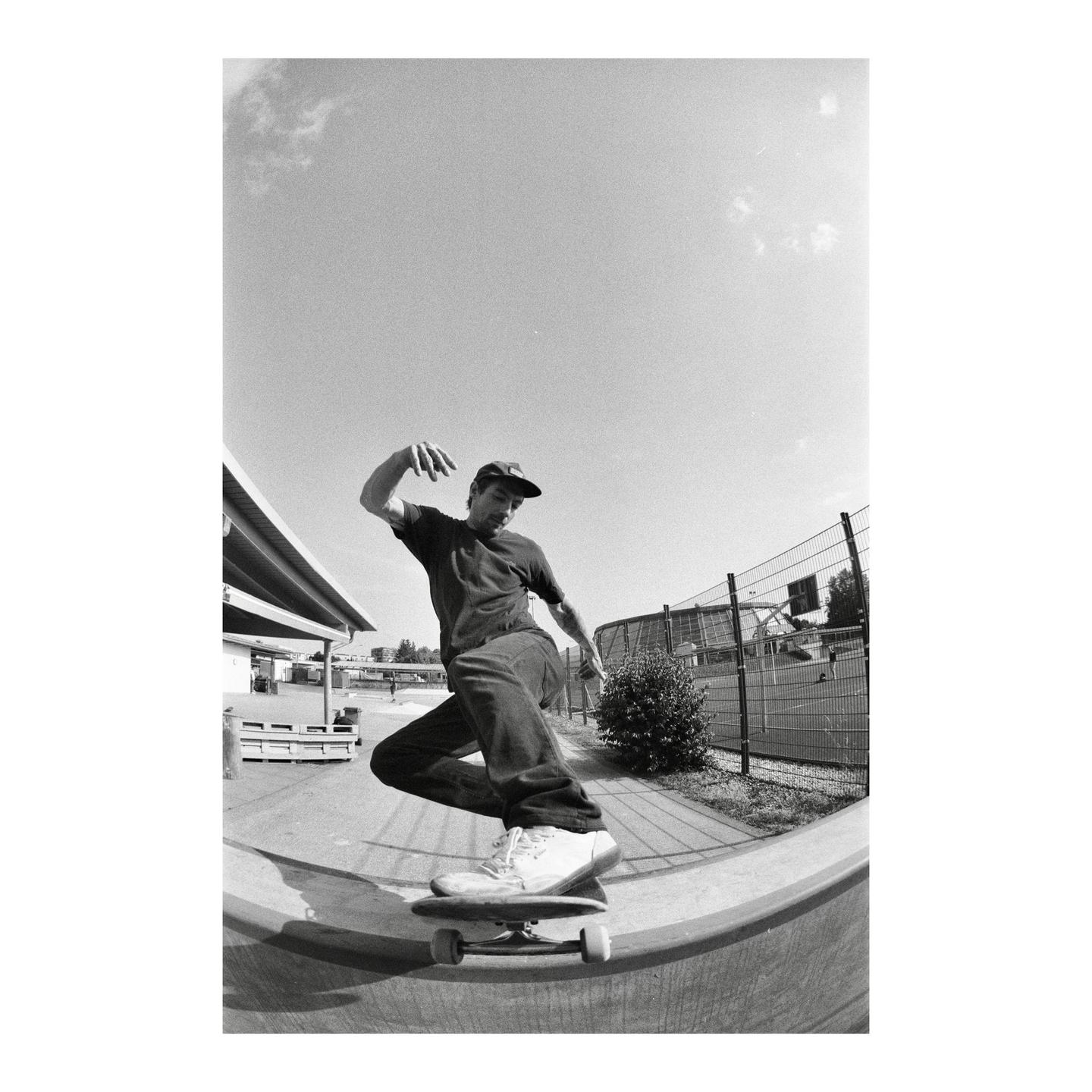 A man on a skateboard rides a concrete ramp at a skatepark.