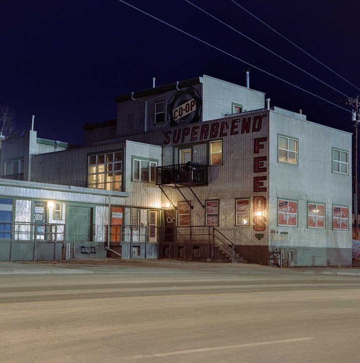 A building with a "Superblend Feeds" sign is illuminated at night.