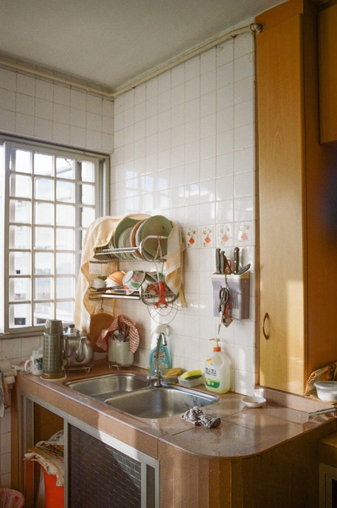 A kitchen with a double sink, a dish drying rack, and a window with grilles.