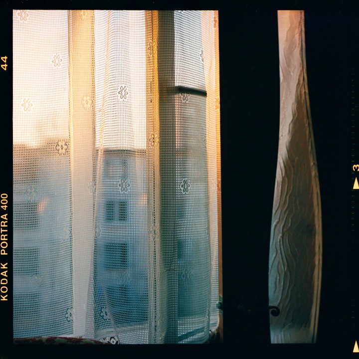 Sunlight streams through a window covered by a sheer curtain, next to a decorative vase.
