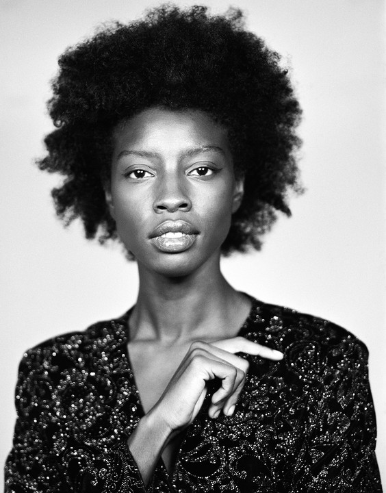 A woman with curly hair and a sequined top looks directly at the viewer.