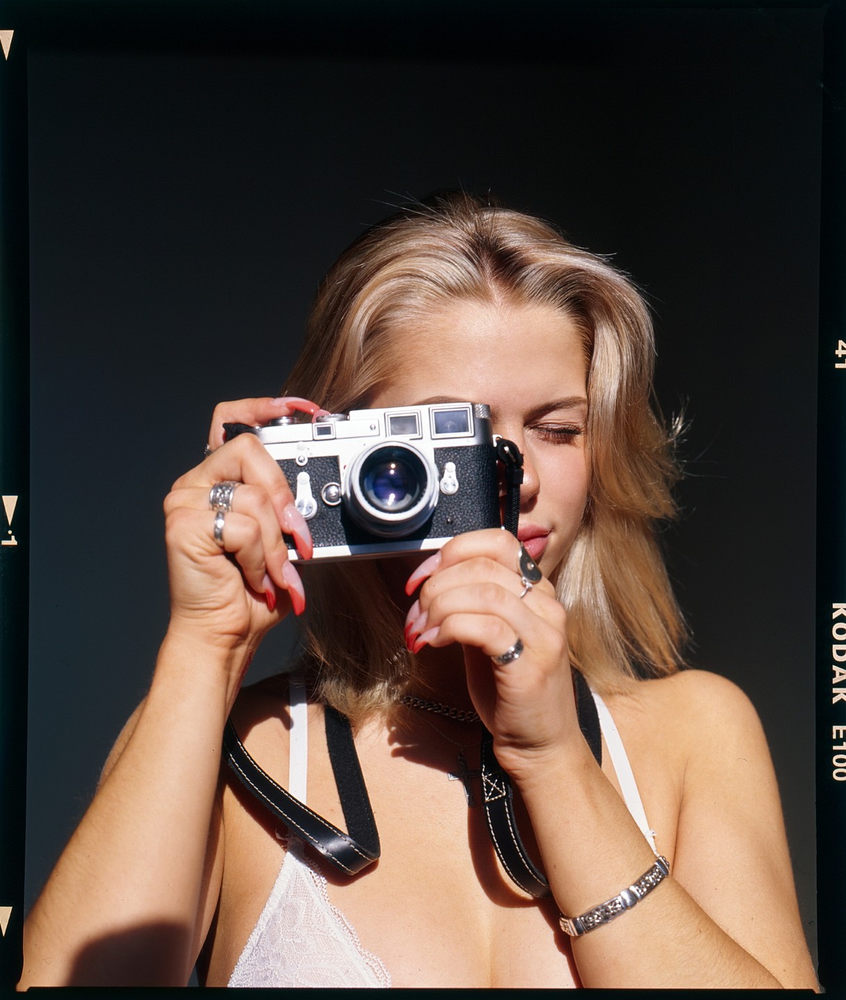 A woman holds a camera up to her face, obscuring her eyes.
