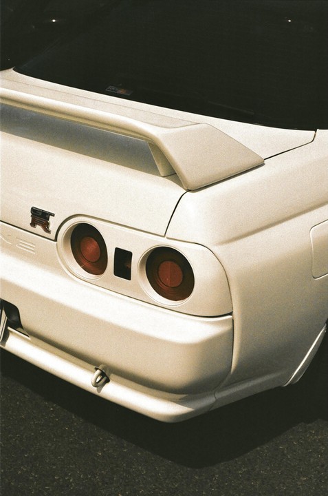 The rear of a white car with a spoiler and round taillights is visible.