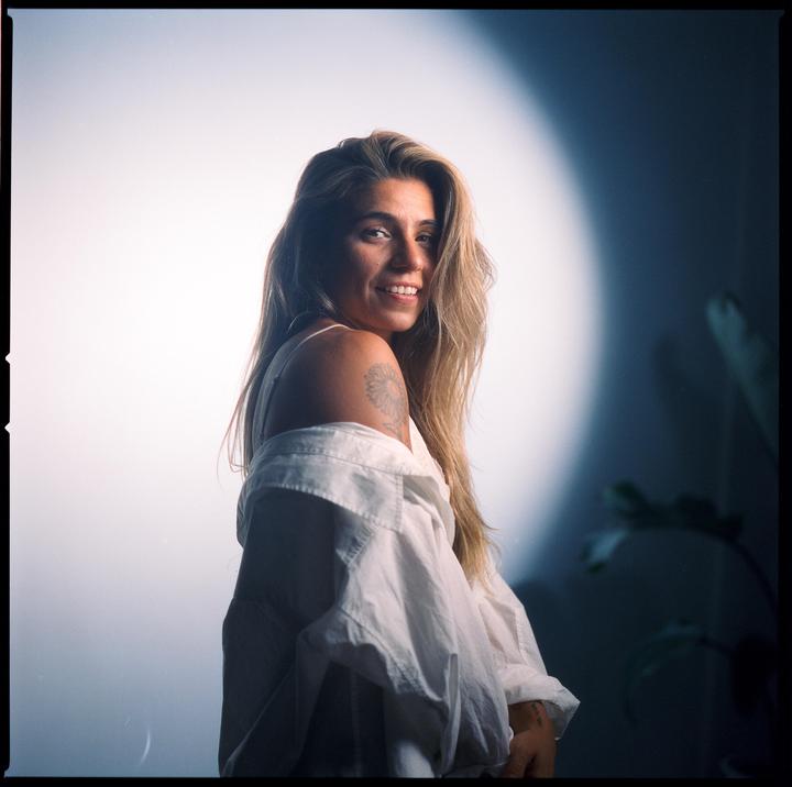 A woman with long hair and a white shirt smiles at the viewer.