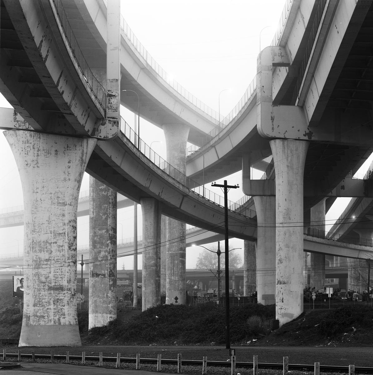 Multiple elevated highway ramps and their support pillars are visible through a hazy atmosphere.