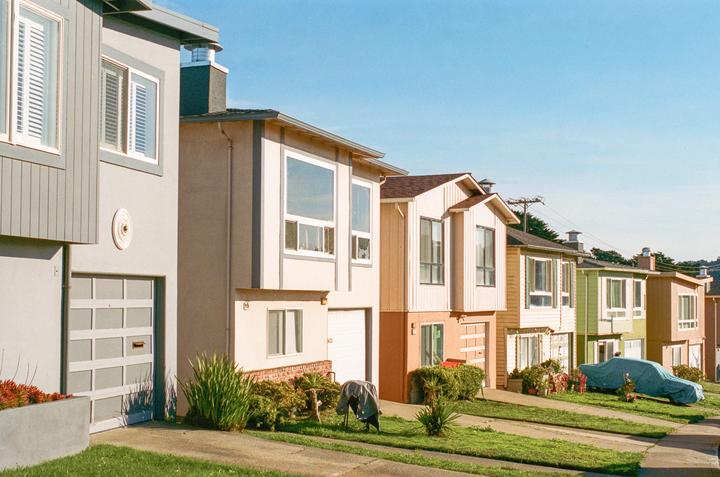 A row of houses with garages and driveways is visible under a clear sky.