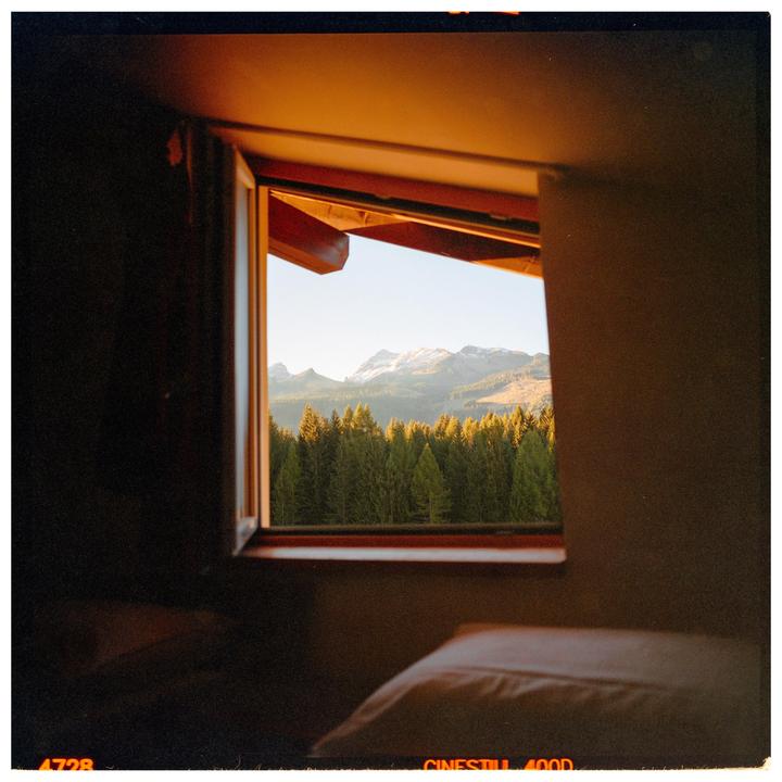 A window looks out onto a forest and snow-capped mountains under a clear sky.