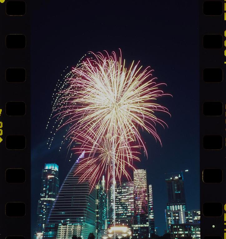 Fireworks explode over a city skyline at night.
