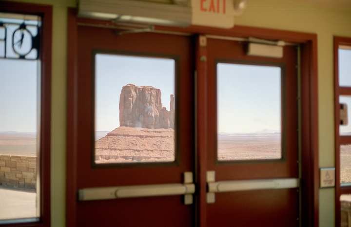 A view of Monument Valley is framed by the windows of a building's exit doors.