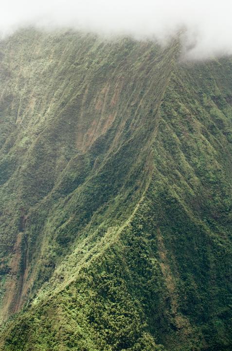 A lush green mountain range is partially obscured by clouds at its peak.