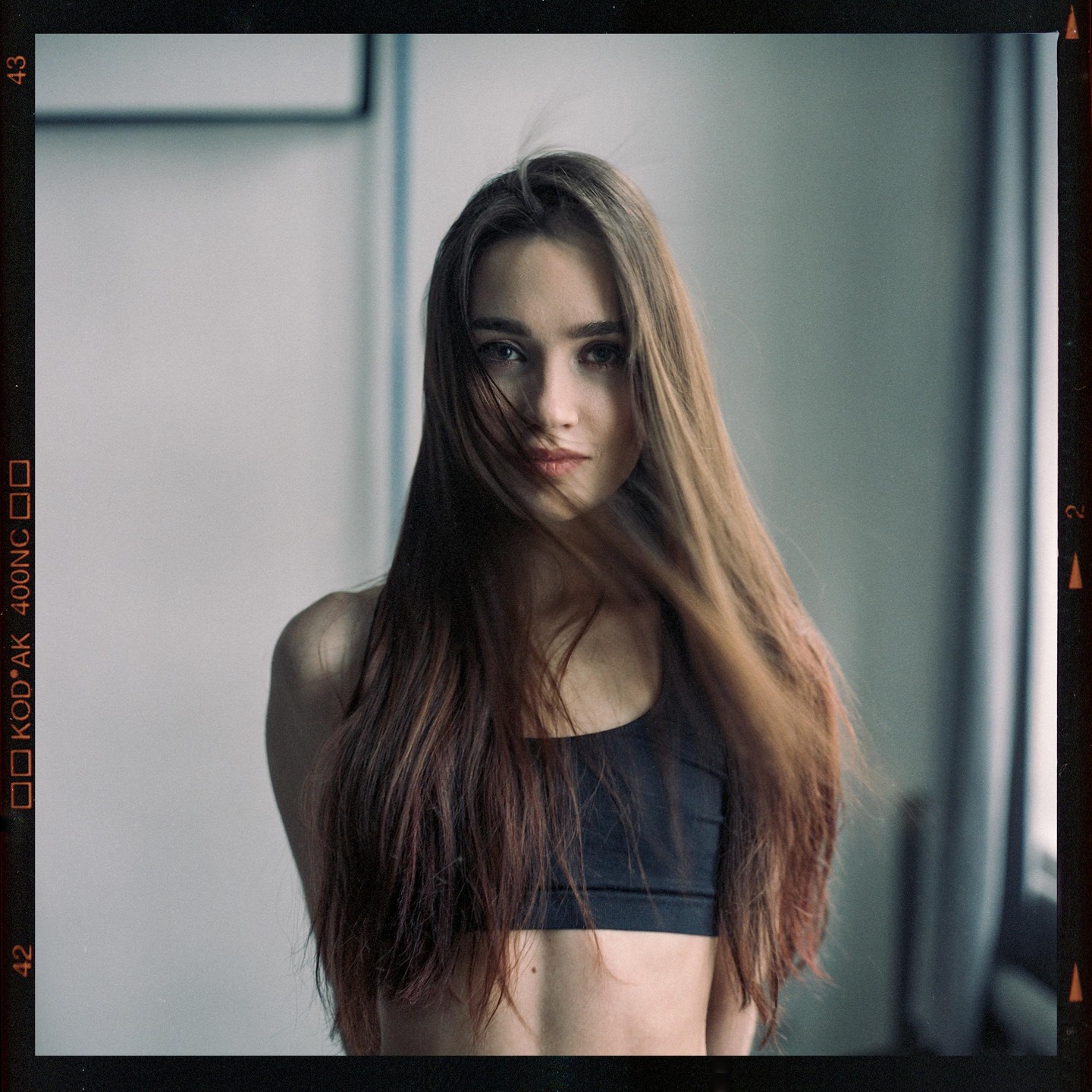 A woman with long hair covering part of her face looks directly at the viewer.
