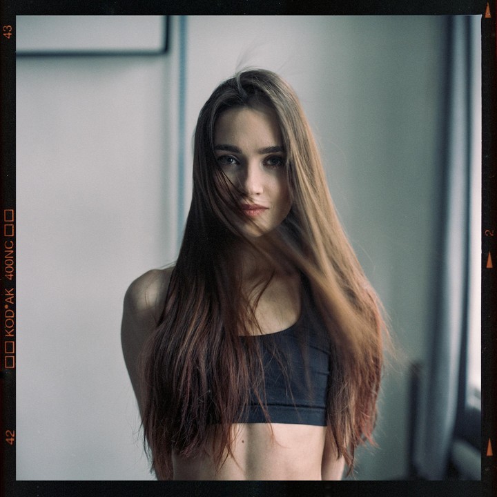 A woman with long hair covering part of her face looks directly at the viewer.
