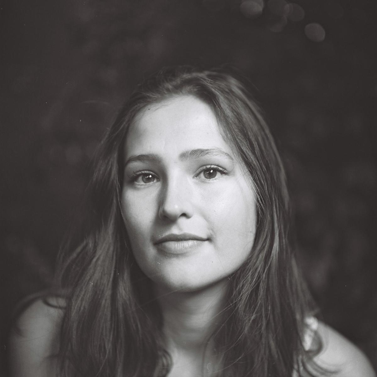 A young woman with long hair looks directly at the viewer.