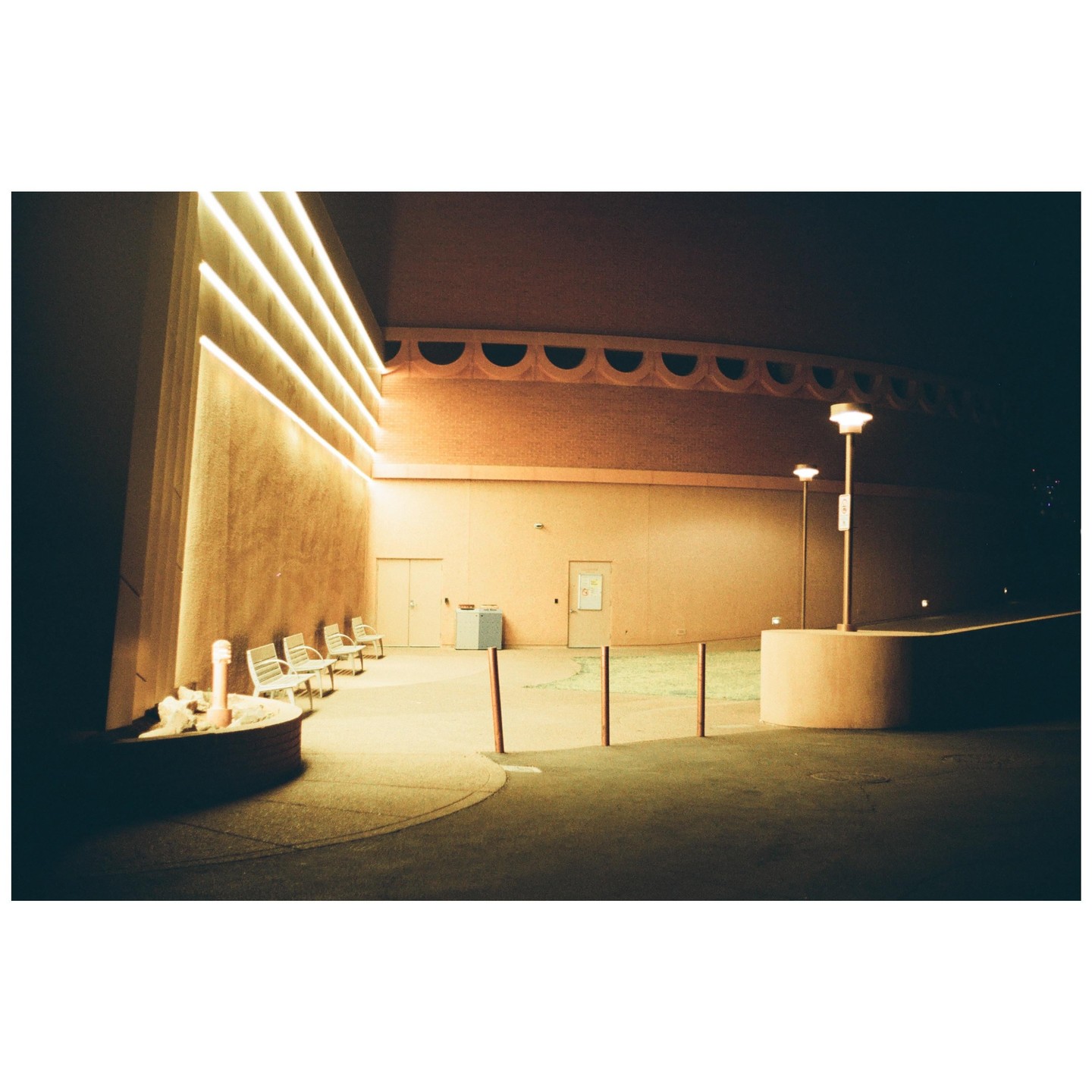 A building with illuminated walls and streetlights stands under a dark night sky.