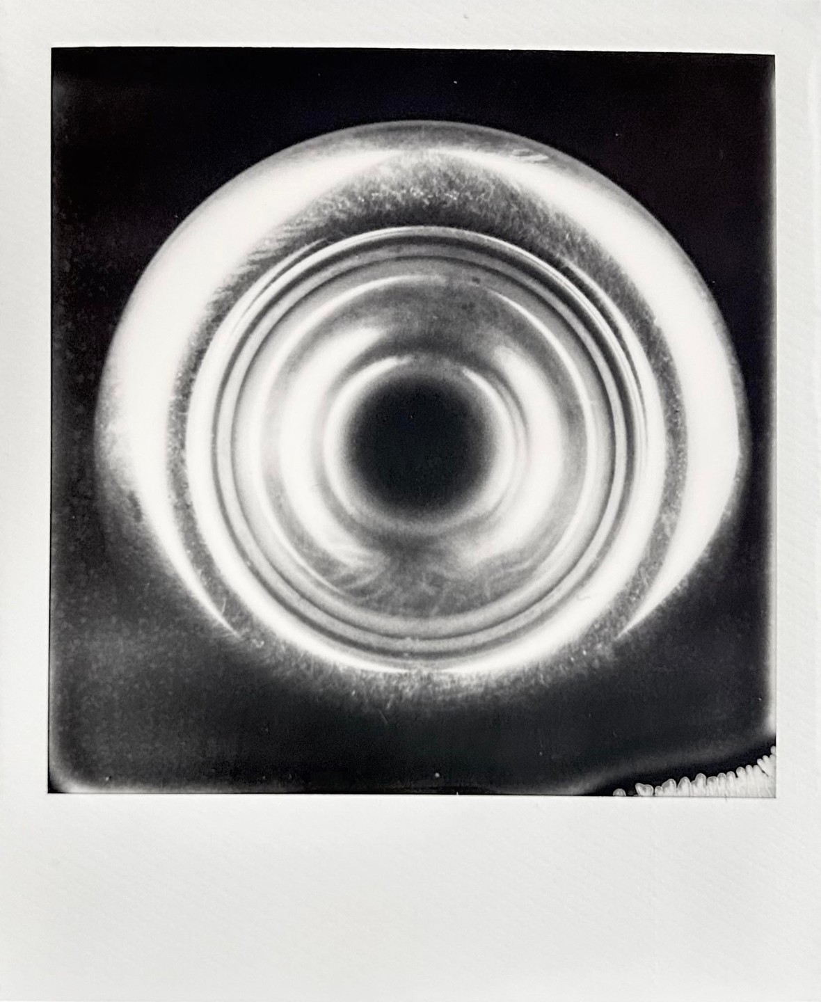 A trumpet mouthpiece is centered in a black and white close-up.