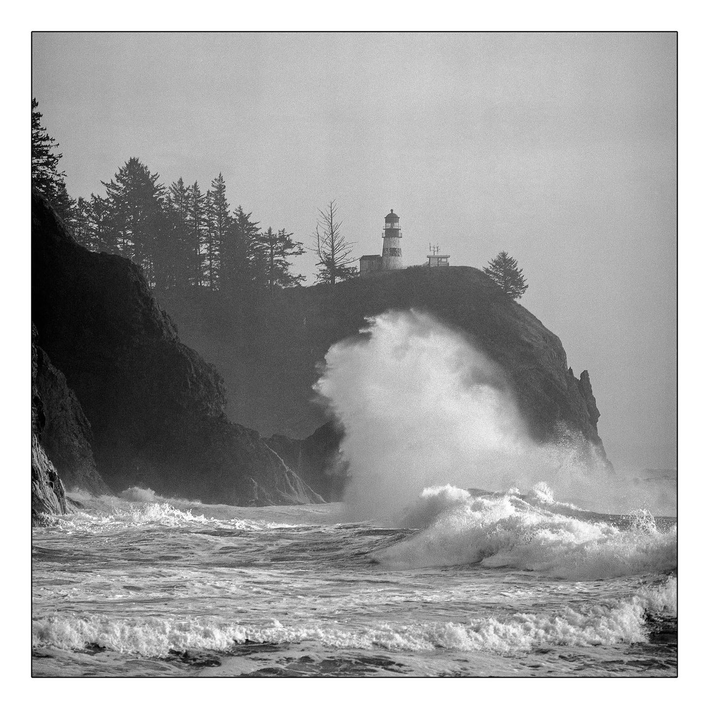 A lighthouse stands on a cliff overlooking a stormy sea with large waves crashing against the shore.