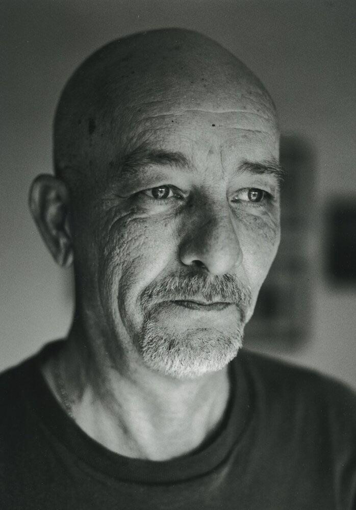 A man with a bald head and a goatee looks away from the camera.