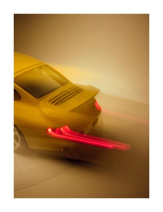 A yellow car with red taillights is blurred, suggesting motion.