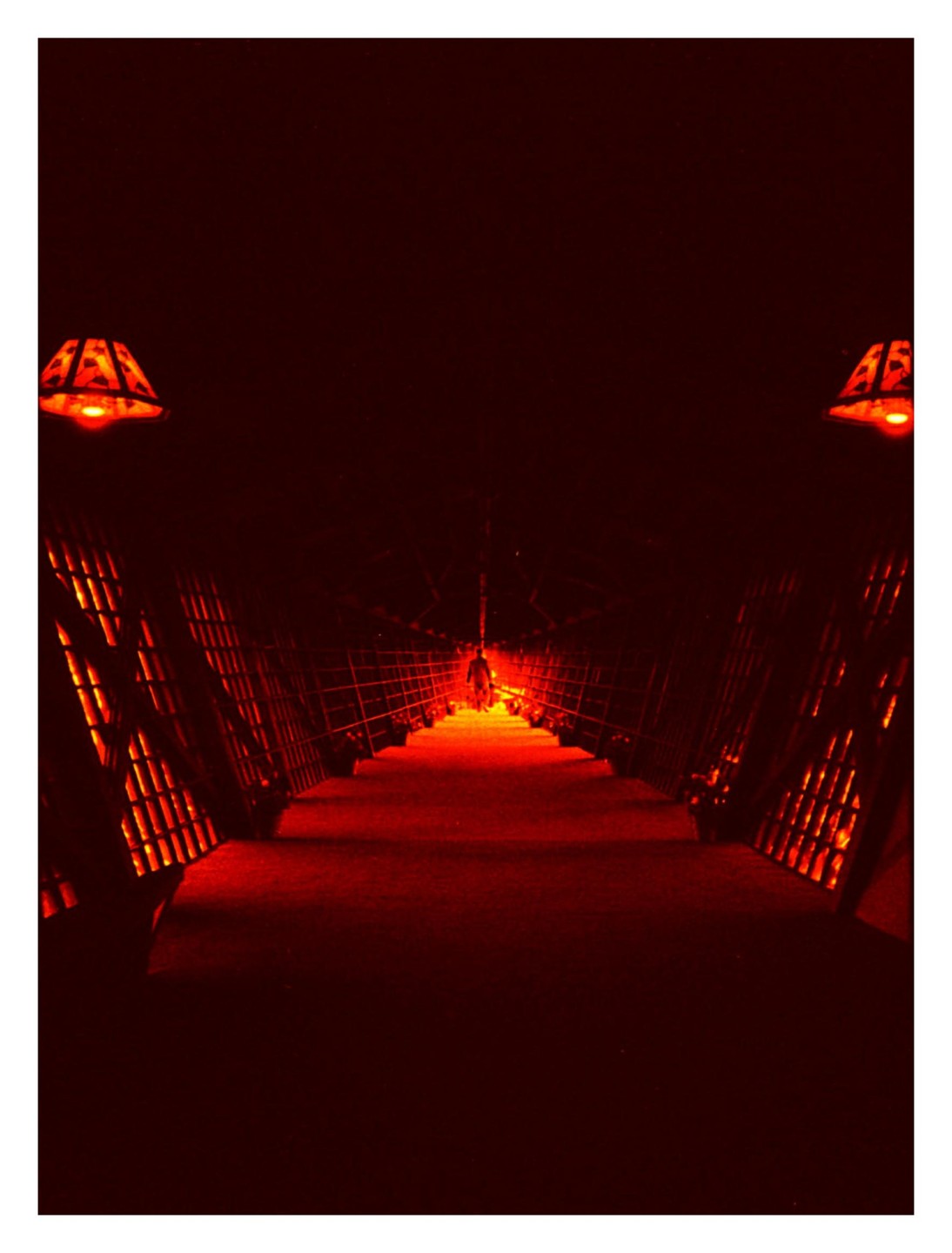 A person walks through a dark tunnel illuminated by red light.