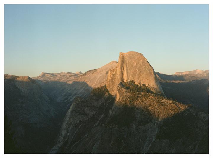 Half Dome is visible in the distance, surrounded by mountains and trees.