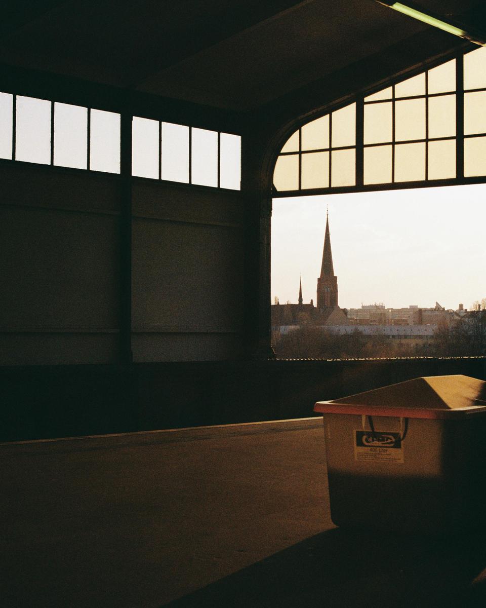 A church steeple is visible through a window from inside a building with a large container in the foreground.